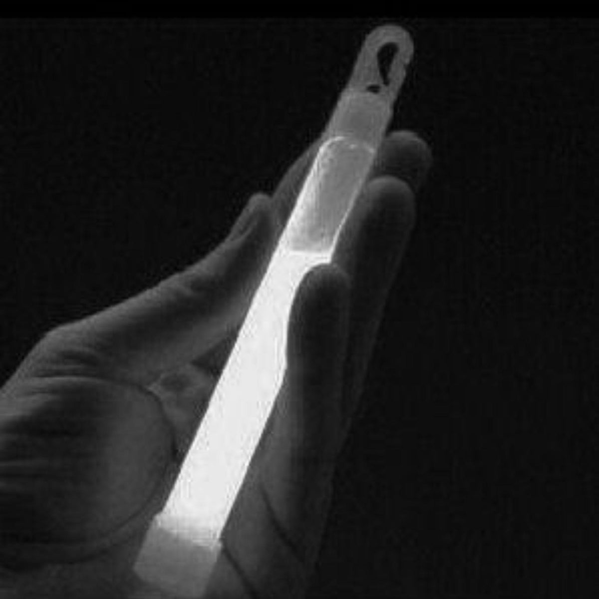 Illuminated NATO 6 inch chemical lightstick held in hand in low-light conditions