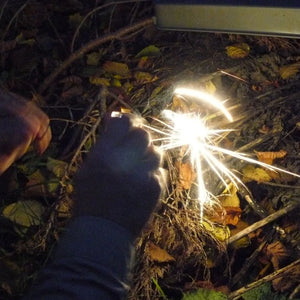 Firefly Champion Spark Marker producing sparks to ignite tinder during an outdoor fire-starting demonstration