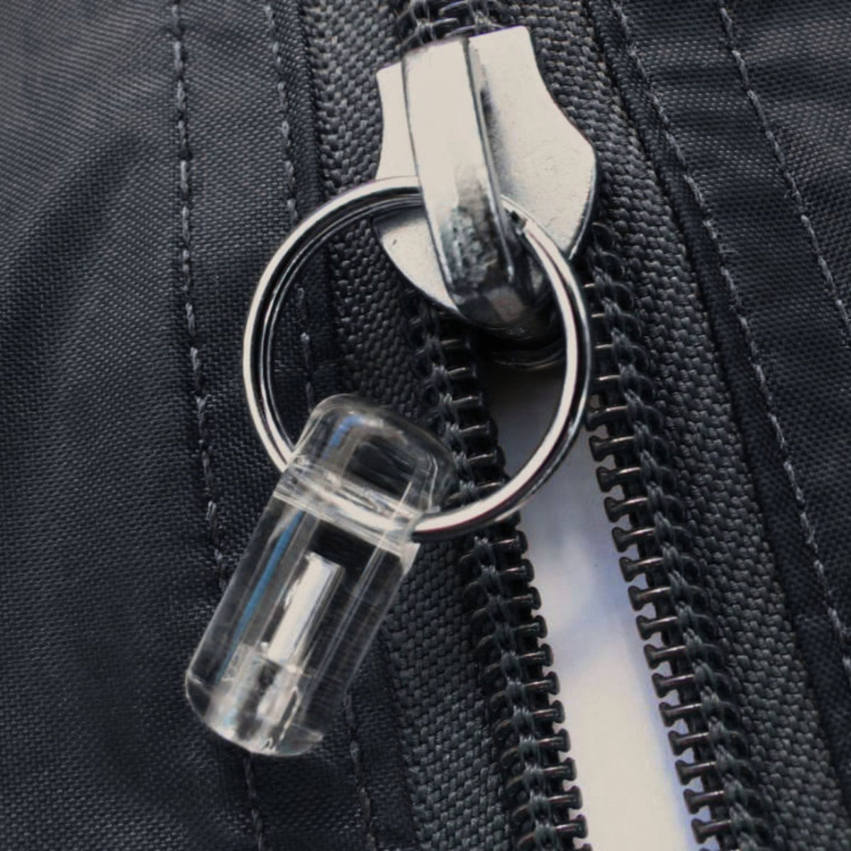 Firefly self-luminous tritium zip marker attached to a black equipment bag using its split-ring attachment